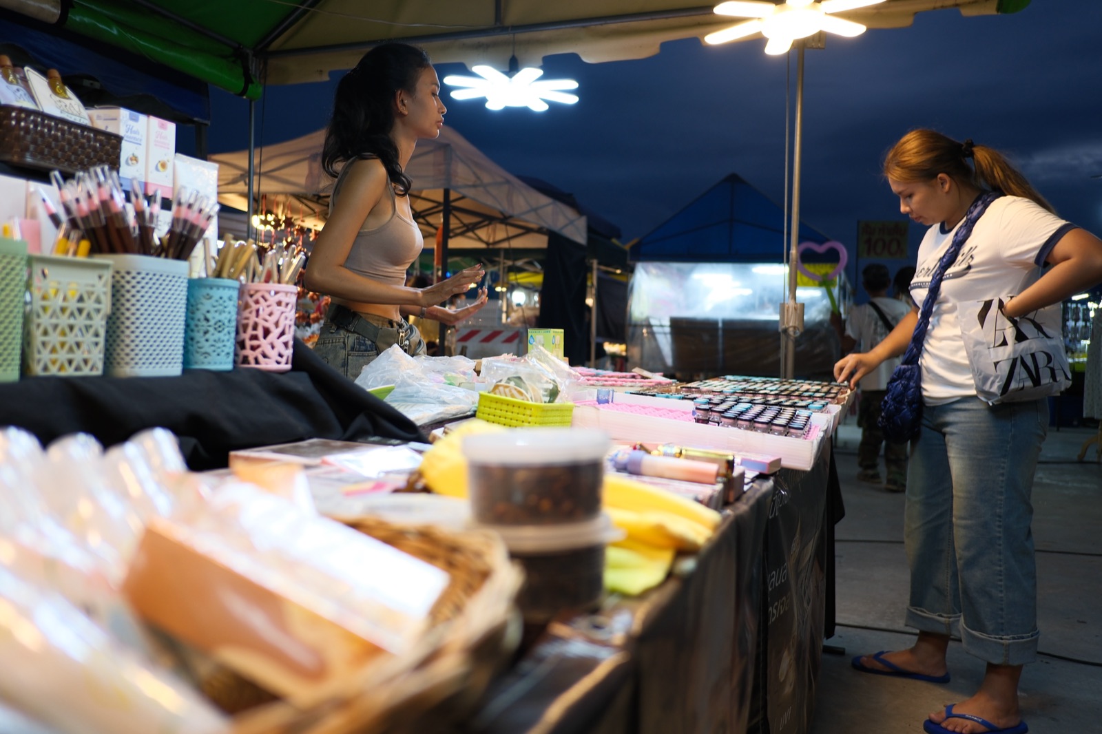 ผู้ซื้อกำลังเลือกสินค้าที่แผงเครื่องสำอางในตลาดกลางคืนประเทศไทย